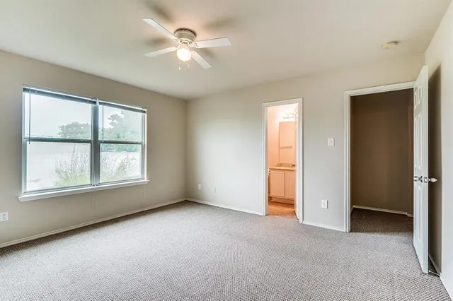 an empty room with chandelier fan and windows