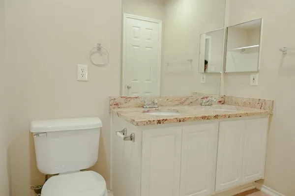 a bathroom with a granite countertop toilet sink and mirror