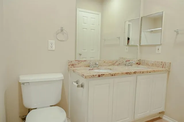 a bathroom with a granite countertop toilet sink and mirror