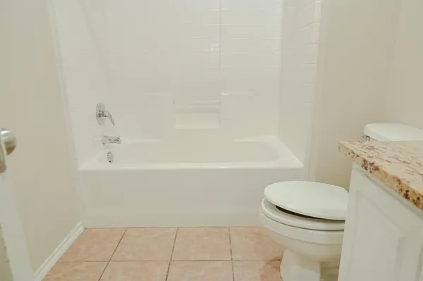 a bathroom with a granite countertop toilet and a bathtub