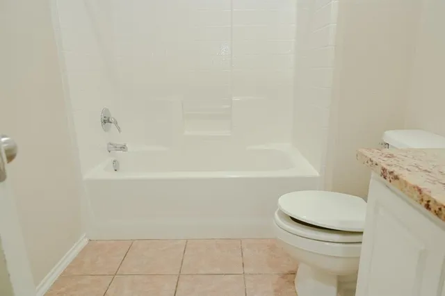 a bathroom with a granite countertop toilet and a bathtub