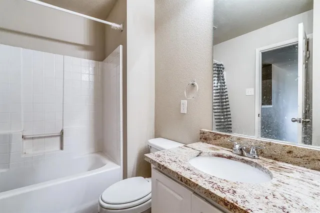 a bathroom with a granite countertop tub sink and mirror