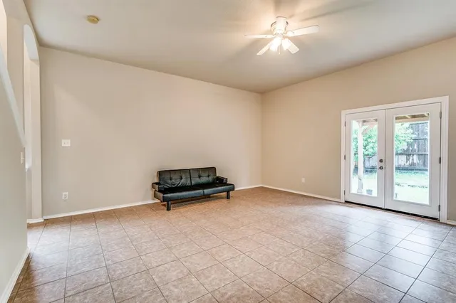 an empty room with windows and ceiling fan