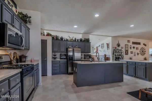 a kitchen with stainless steel appliances granite countertop a stove top oven a sink dishwasher a refrigerator and a dining table with wooden floor