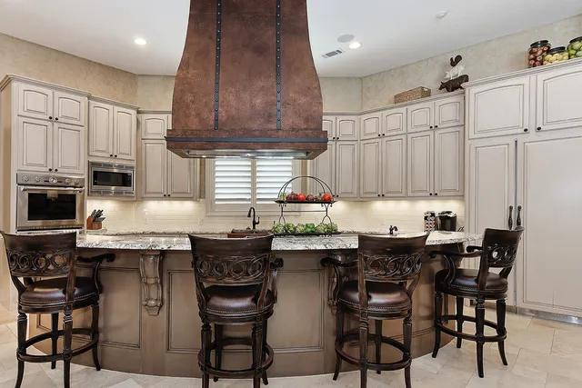 a kitchen with stainless steel appliances granite countertop a table chairs sink and cabinets