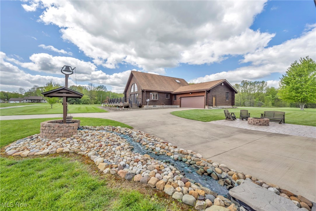 15180 Stoltz Road Diamond, OH 44412 - Photo 4 of 48 View of side of property with an outdoor fire pit, a front lawn, driveway, a garage, and a shingled roof