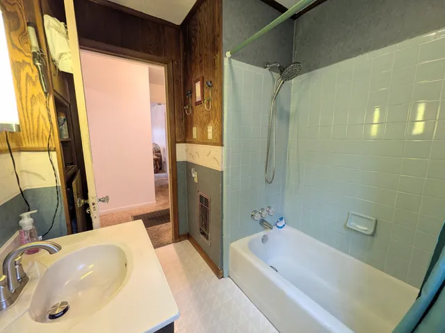 a bathroom with a tub a sink and a large mirror