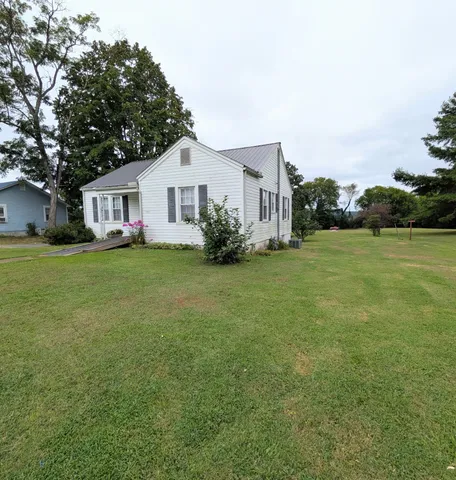 a view of a house with a big yard and large trees