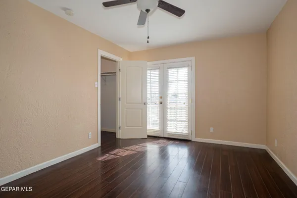 an empty room with wooden floor cabinet and windows