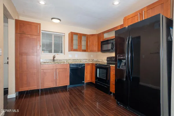 a kitchen with granite countertop a refrigerator stove top oven and sink