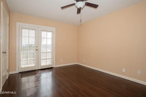 an empty room with wooden floor fan and windows