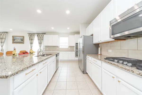 a large kitchen with stainless steel appliances kitchen island granite countertop a sink and cabinets