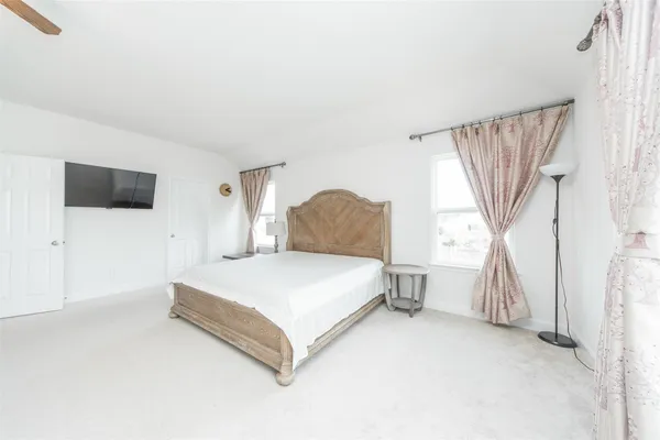 a spacious bedroom with a bed and a flat screen tv