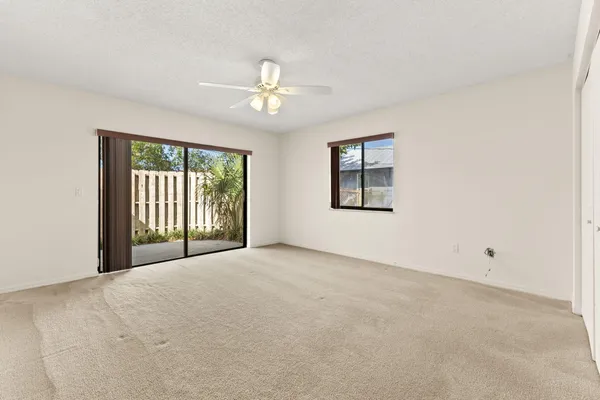 an empty room with windows and ceiling fan