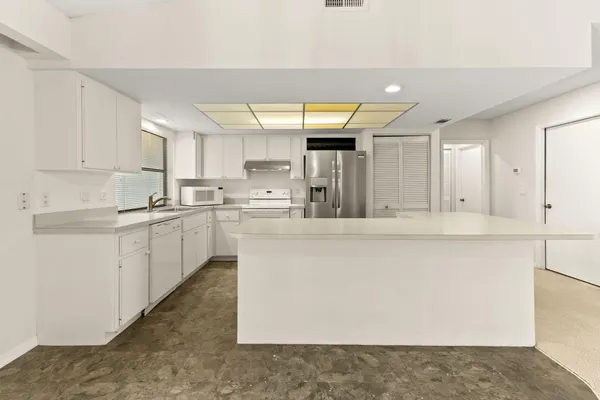 a kitchen with stainless steel appliances a refrigerator and white cabinets