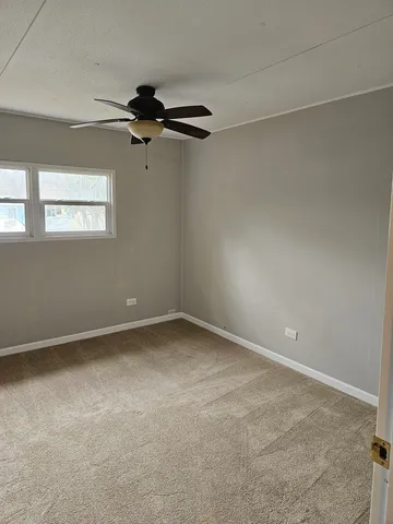 an empty room with a ceiling fan and a window