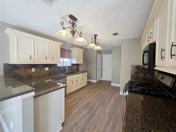 a kitchen with kitchen island granite countertop a sink cabinets and stainless steel appliances