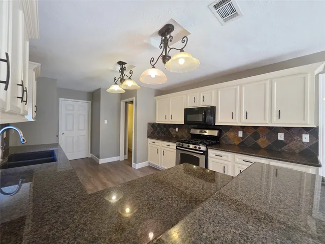 a kitchen with stainless steel appliances granite countertop a sink dishwasher a stove and a refrigerator with wooden floor