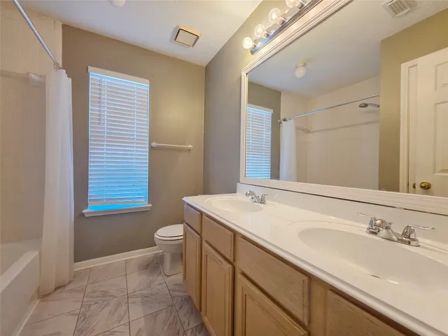 a bathroom with a sink a toilet a mirror and shower