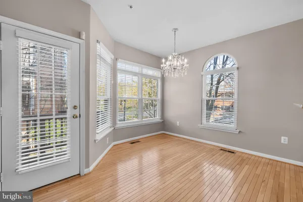 a view of an empty room with wooden floor fireplace and a window
