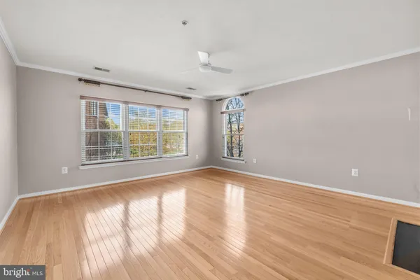 an empty room with wooden floor a fireplace and windows