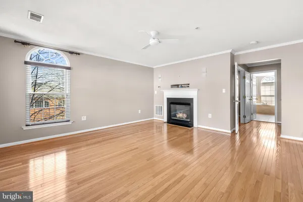 a view of an empty room with wooden floor fireplace and a window