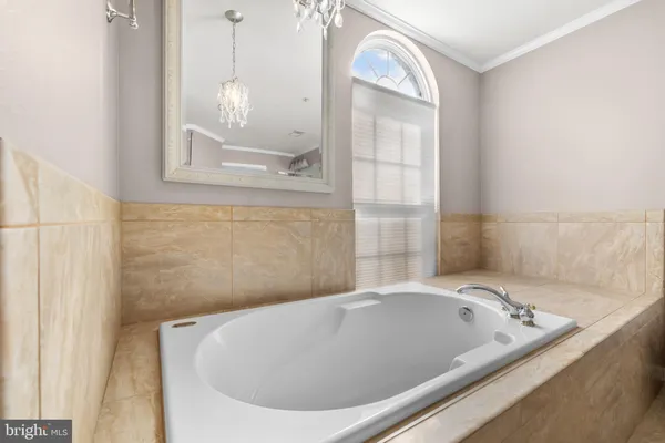 a view of spacious bathroom with a tub and chandelier