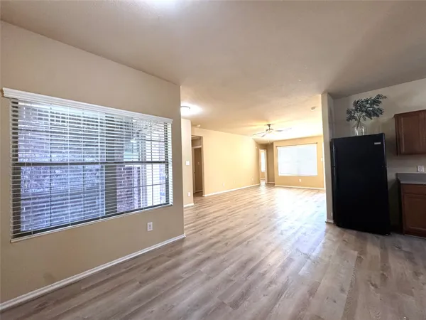 a view of an empty room with a window and wooden floor