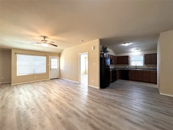 a view of kitchen and empty room with wooden floor
