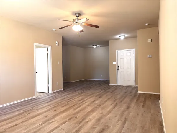 an empty room with wooden floor and fan