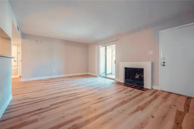 a view of empty room with wooden floor and fireplace
