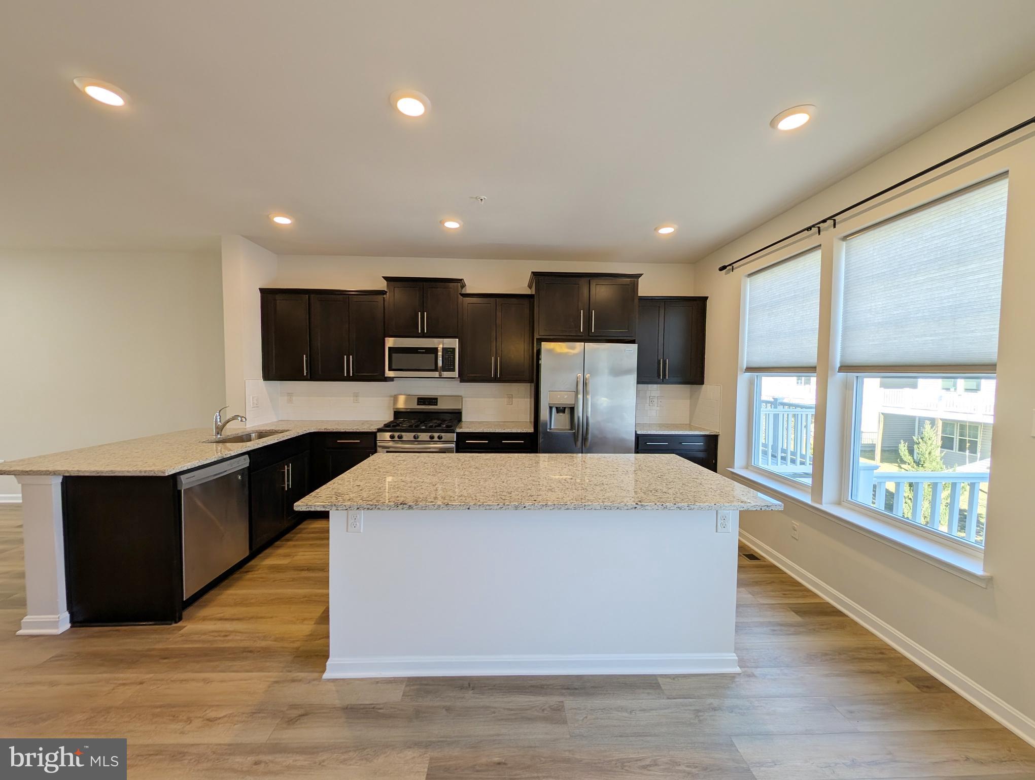 3106 Laurel Hill Road Hanover, MD 21076 - Photo 6 of 27 a large kitchen with stainless steel appliances kitchen island a large counter top and a wooden floors