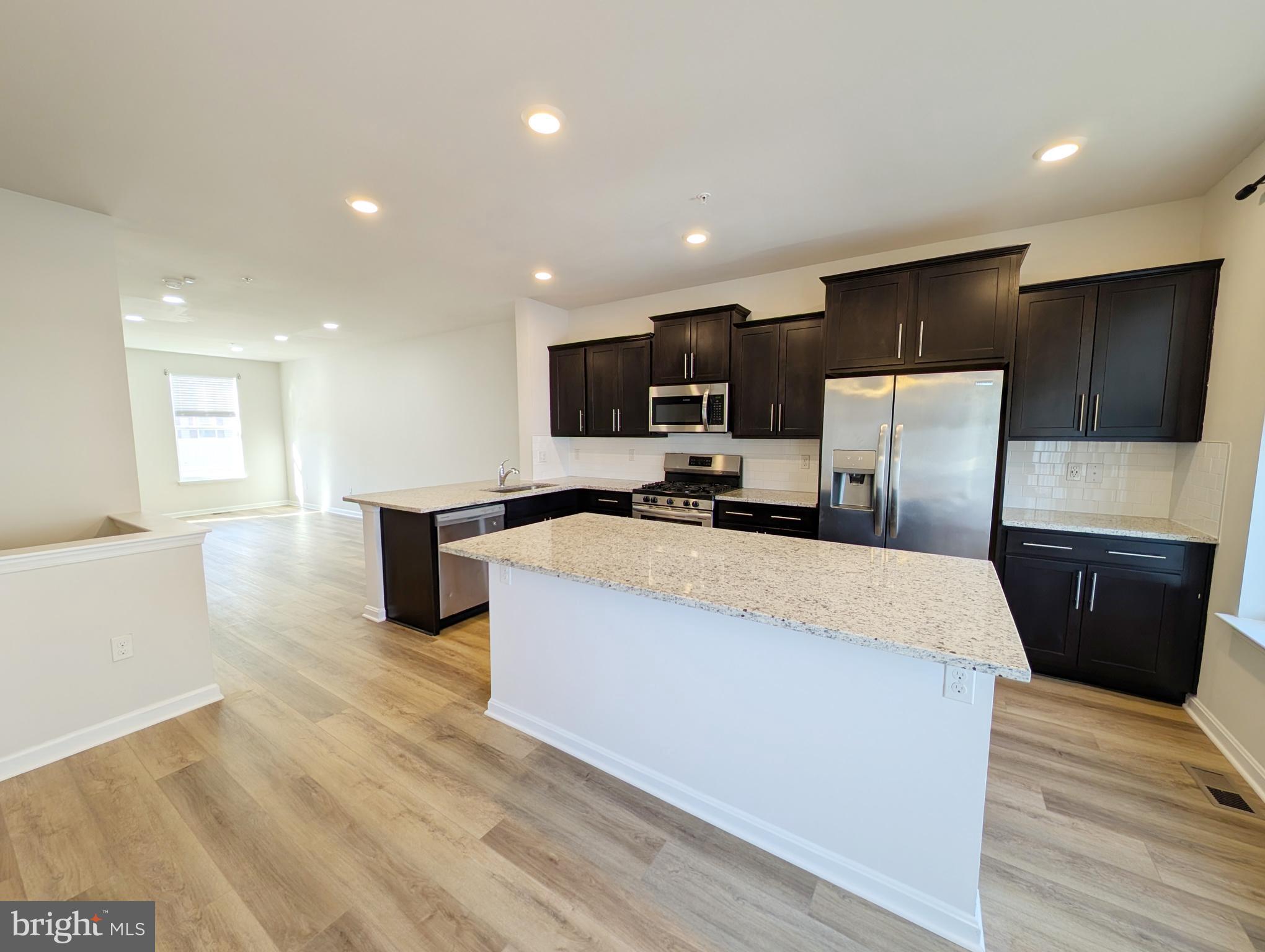 3106 Laurel Hill Road Hanover, MD 21076 - Photo 7 of 27 a large kitchen with stainless steel appliances kitchen island granite countertop a sink a stove a microwave a counter top and a floors