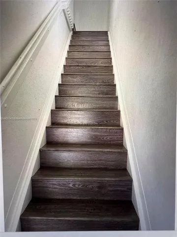 a view of a hallway with wooden floor and stairs