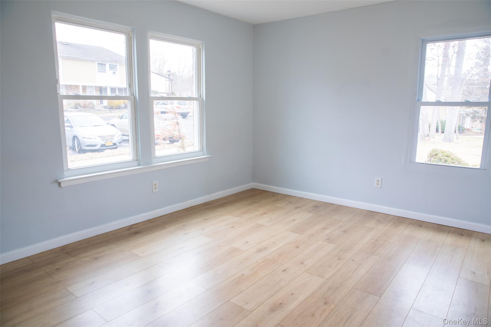 1 A Jamestown Court Ridge, NY 11961 - Photo 5 of 15 an empty room with wooden floor and windows