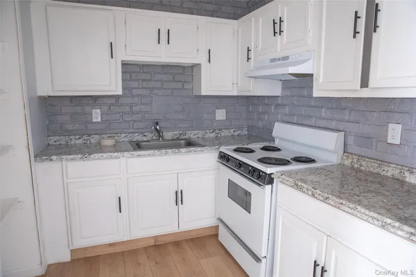 a kitchen with granite countertop white cabinets and white appliances
