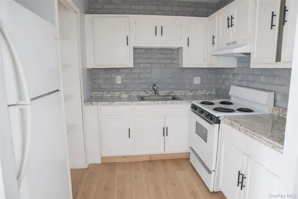 a kitchen with granite countertop white cabinets and white appliances