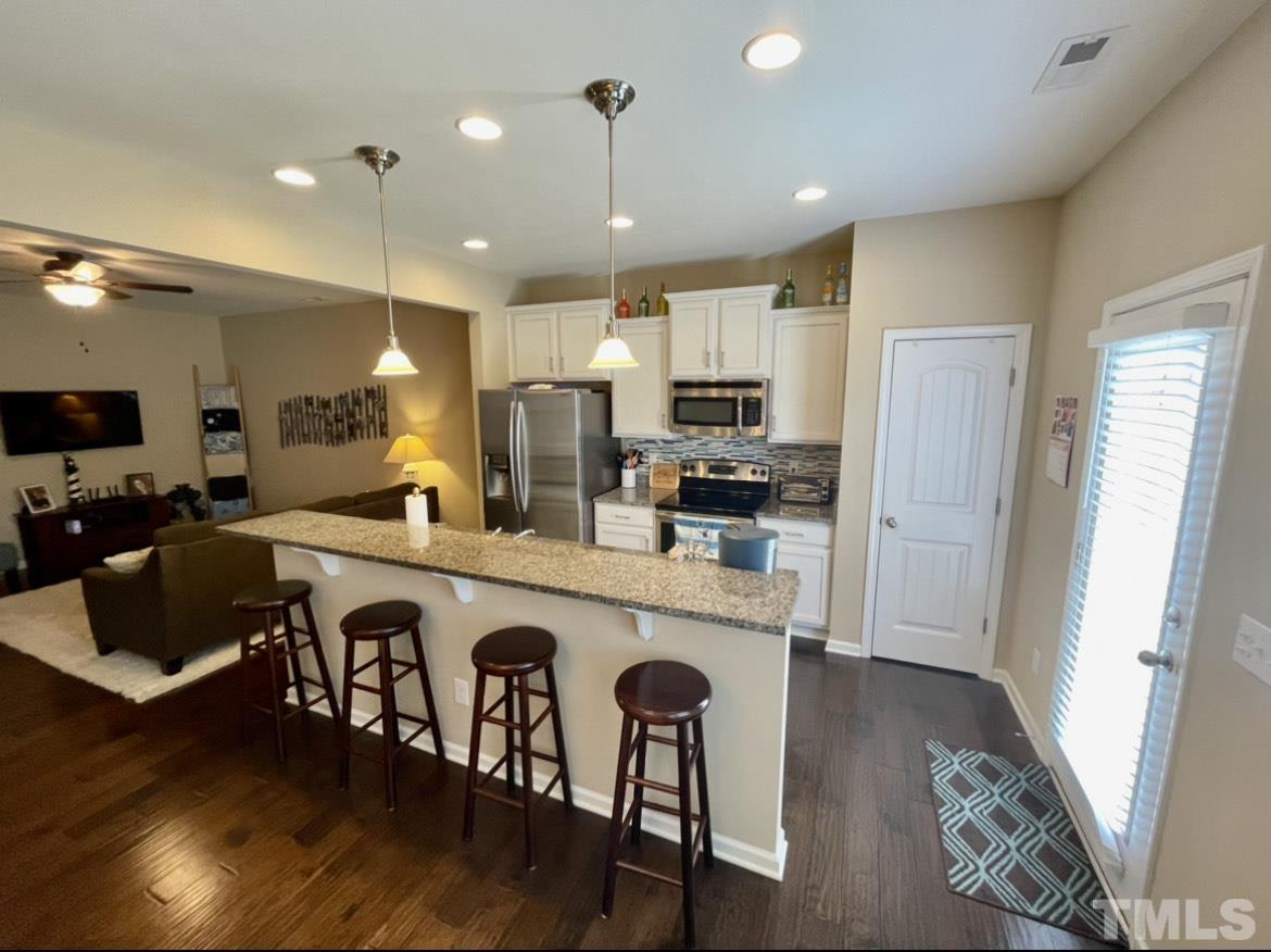 306 Leighann Ridge Lane Rolesville, NC 27571 - Photo 5 of 13 a kitchen with stainless steel appliances granite countertop a refrigerator a stove top oven a sink dishwasher and white cabinets with wooden floor