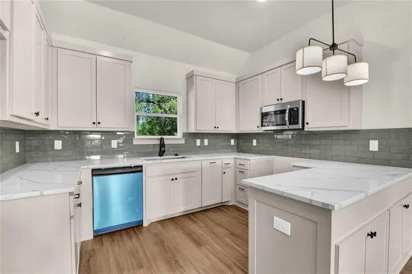 a kitchen with kitchen island granite countertop stainless steel appliances a stove a sink and a white cabinets