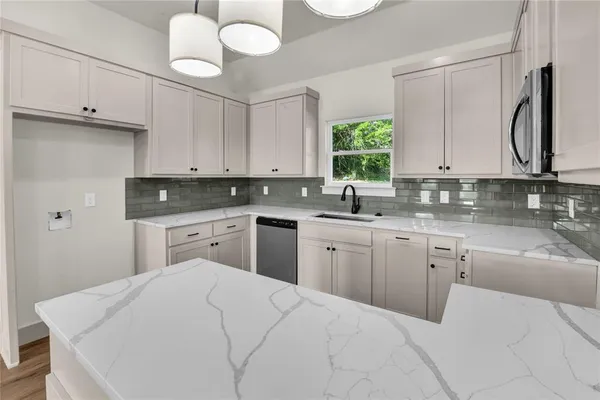 a kitchen with granite countertop a sink a window and cabinets