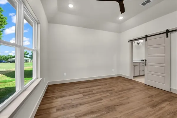 a view of an empty room with a window and wooden floor