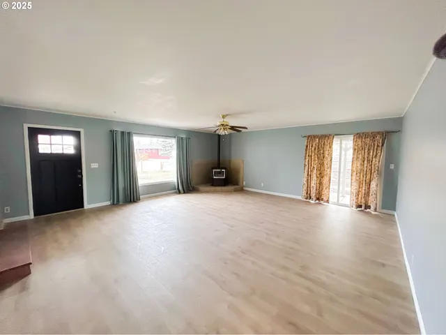 a view of an empty room with window and wooden floor