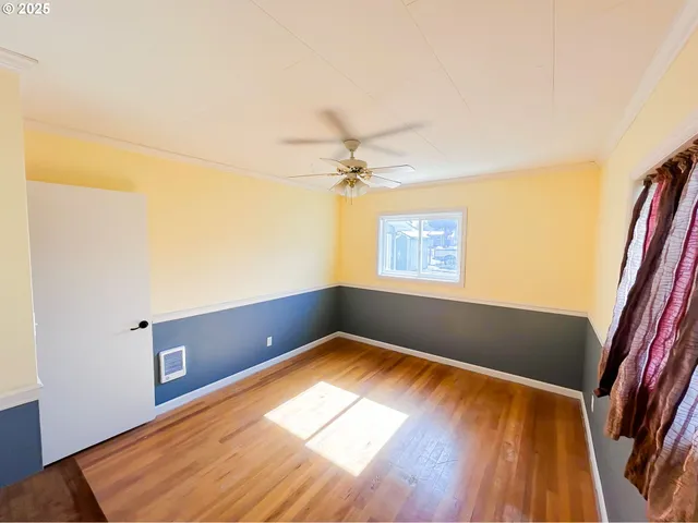 an empty room with wooden floor chandelier fan and windows