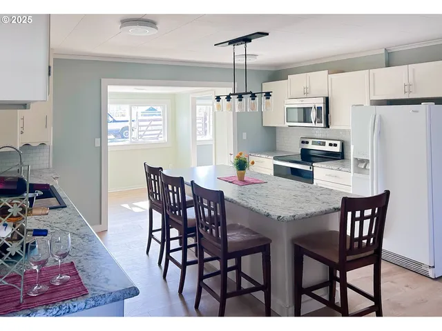 a kitchen with stainless steel appliances kitchen island granite countertop a sink a stove and a refrigerator
