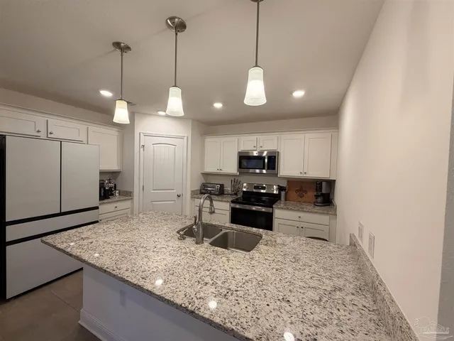 a kitchen with stainless steel appliances granite countertop a sink a stove and a wooden floors