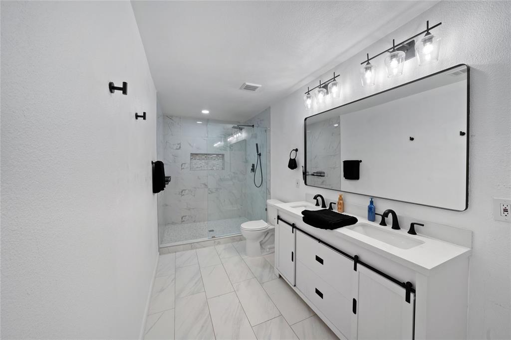 1301 Thoreau Lane Allen, TX 75002 - Photo 13 of 31 a spacious bathroom with a double vanity sink a toilet a mirror and shower