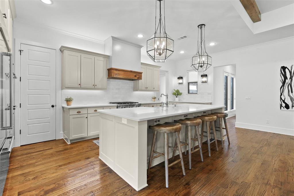 a kitchen with stainless steel appliances kitchen island granite countertop a wooden floor and white cabinets