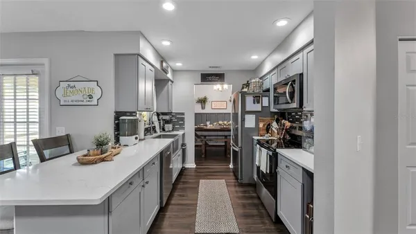 a kitchen with stainless steel appliances kitchen island granite countertop a refrigerator and a sink