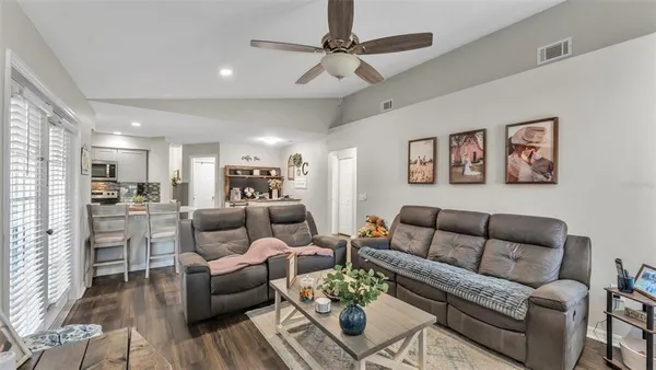 a living room with furniture kitchen view and a wooden floor