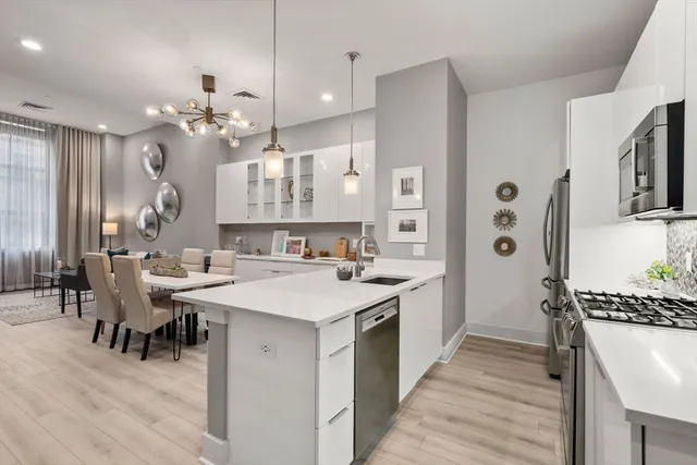 a large kitchen with cabinets a sink a stove a dining table and chairs